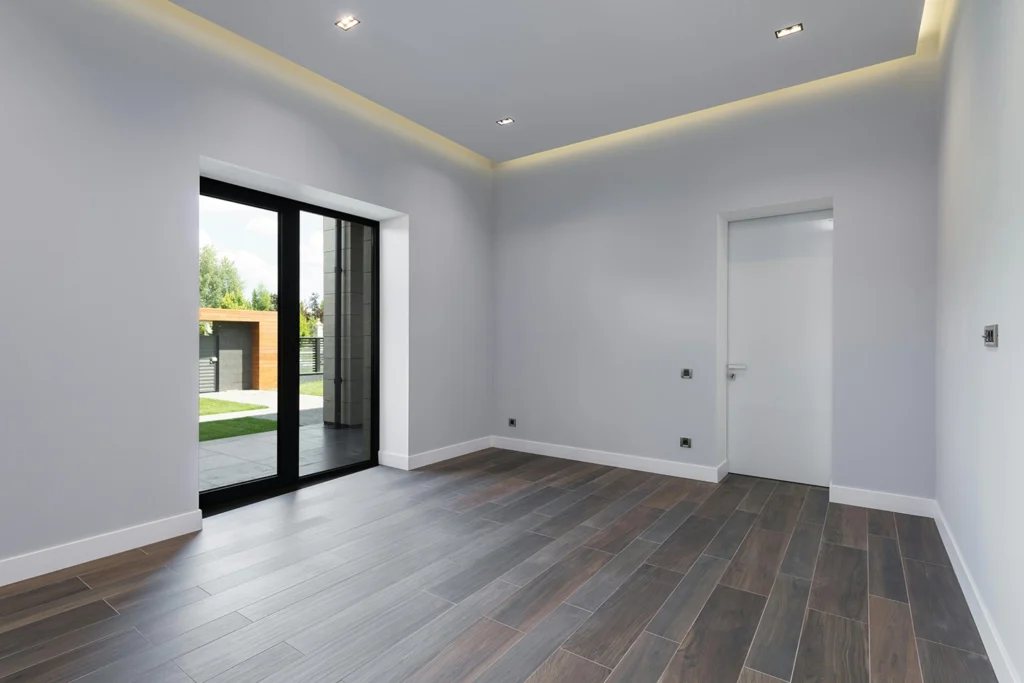 Pièce à vivre au murs gris clair avec lumières intégrées et parquet foncé